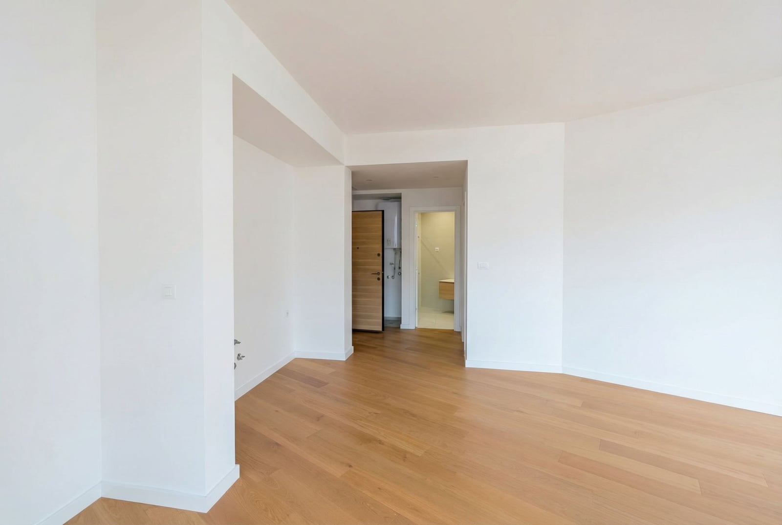 Bright living room with parquet flooring in a new apartment in Becici, Montenegro, view of the hallway and bathroom.