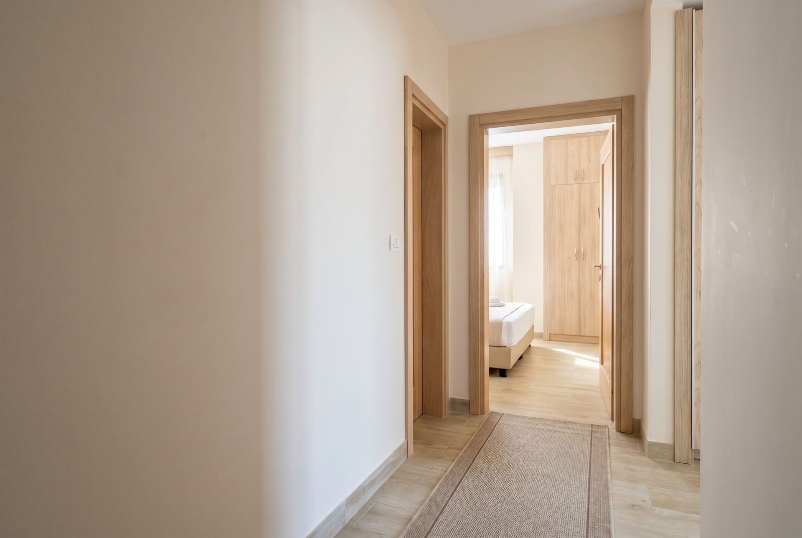 Bright hallway in an apartment in Bečići, Montenegro: view of the bedroom with wooden furniture and high-quality finishes.