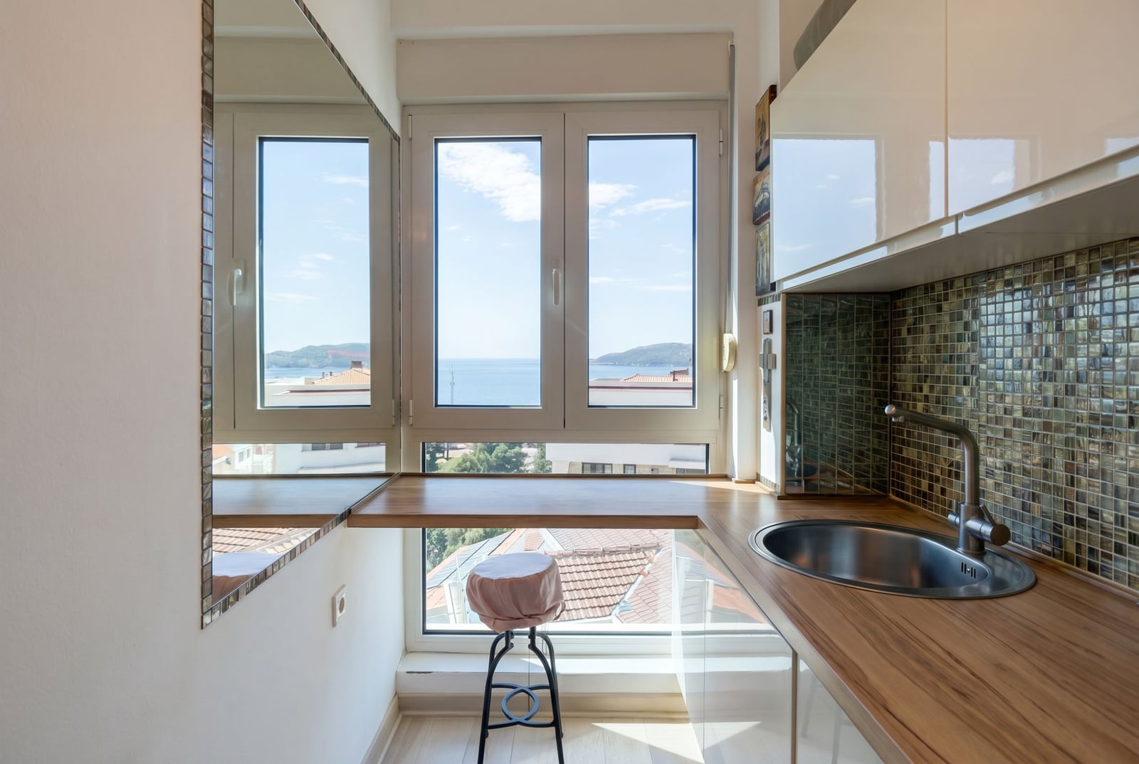Kitchen with a breakfast bar by the window and sea view in an apartment in Becici, Montenegro: modern finishes and glossy fronts.