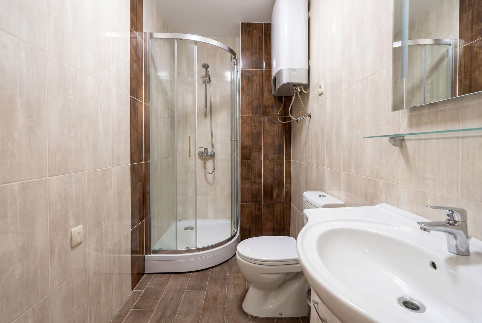 Bathroom in an apartment in Bečići, Montenegro: shower cabin, sanitary ware, and brown-toned tile finishes.
