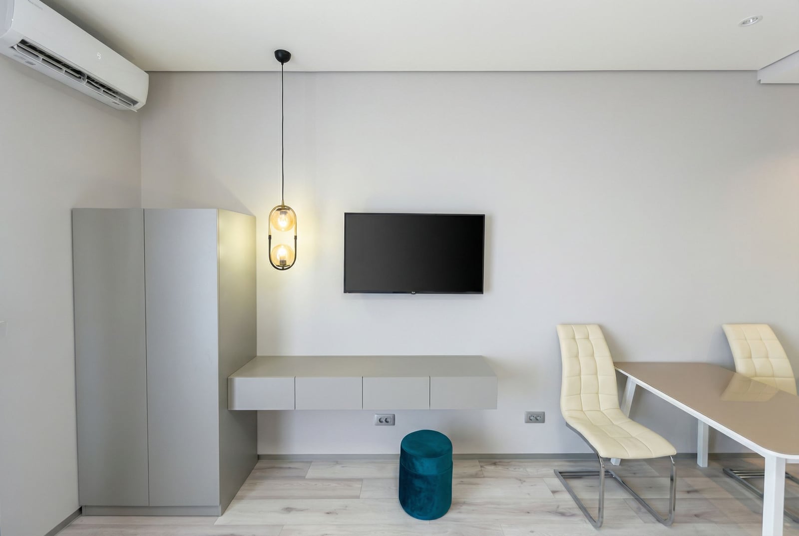 Modern living room in an apartment, Becici, Montenegro: TV area, floating console, stylish chairs, and air conditioner.
