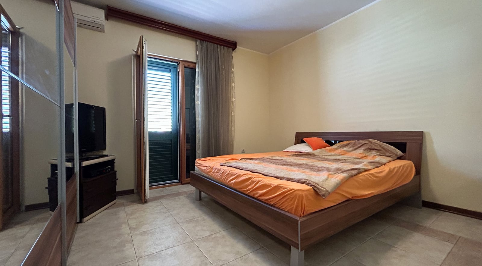 Bedroom with a double bed, wardrobe, and access to the balcony in a villa, Dobrota, Montenegro.