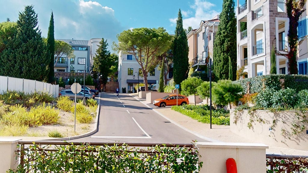 Residential complex in Luštica, Montenegro: modern architecture, well-maintained grounds, parking, and cypress trees.