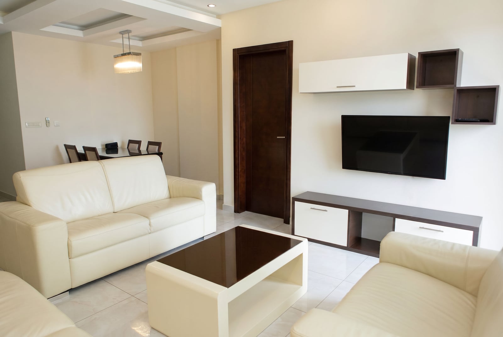 Modern living room with white leather sofas in an apartment in Becici, Montenegro: stylish interior and TV area.