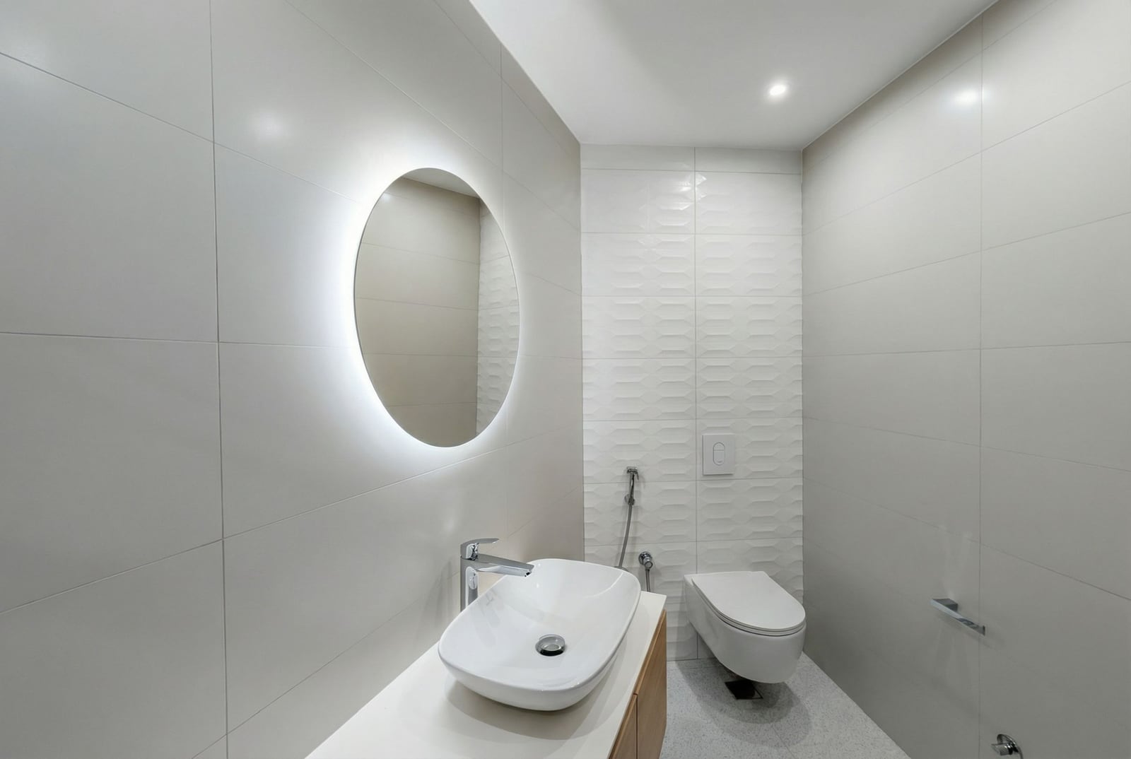 Modern bathroom in an apartment in Bečići, Montenegro: wall-hung toilet, countertop sink, and round LED mirror.
