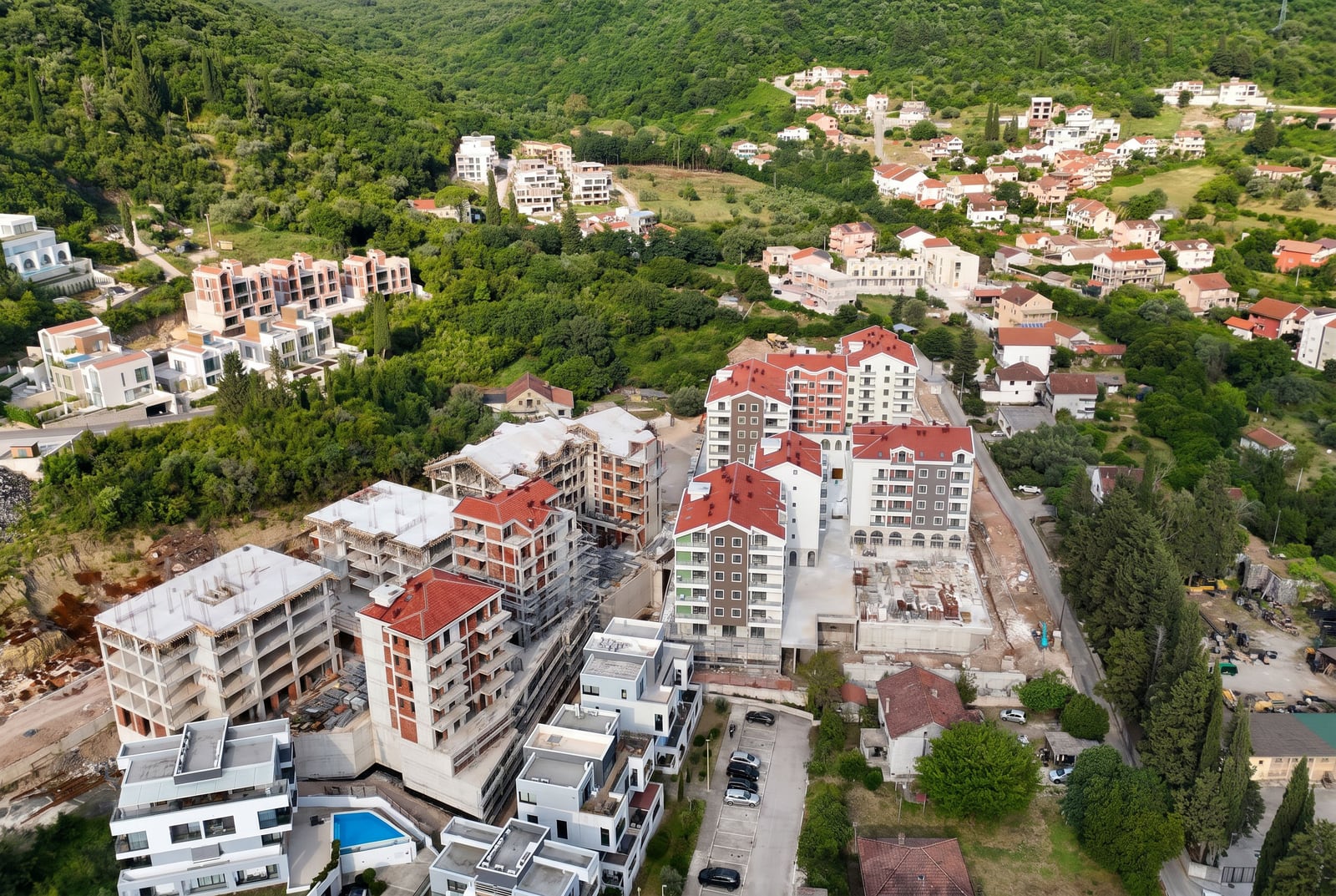 Aerial view of a residential complex under construction with red roofs and a swimming pool in Tivat, Montenegro