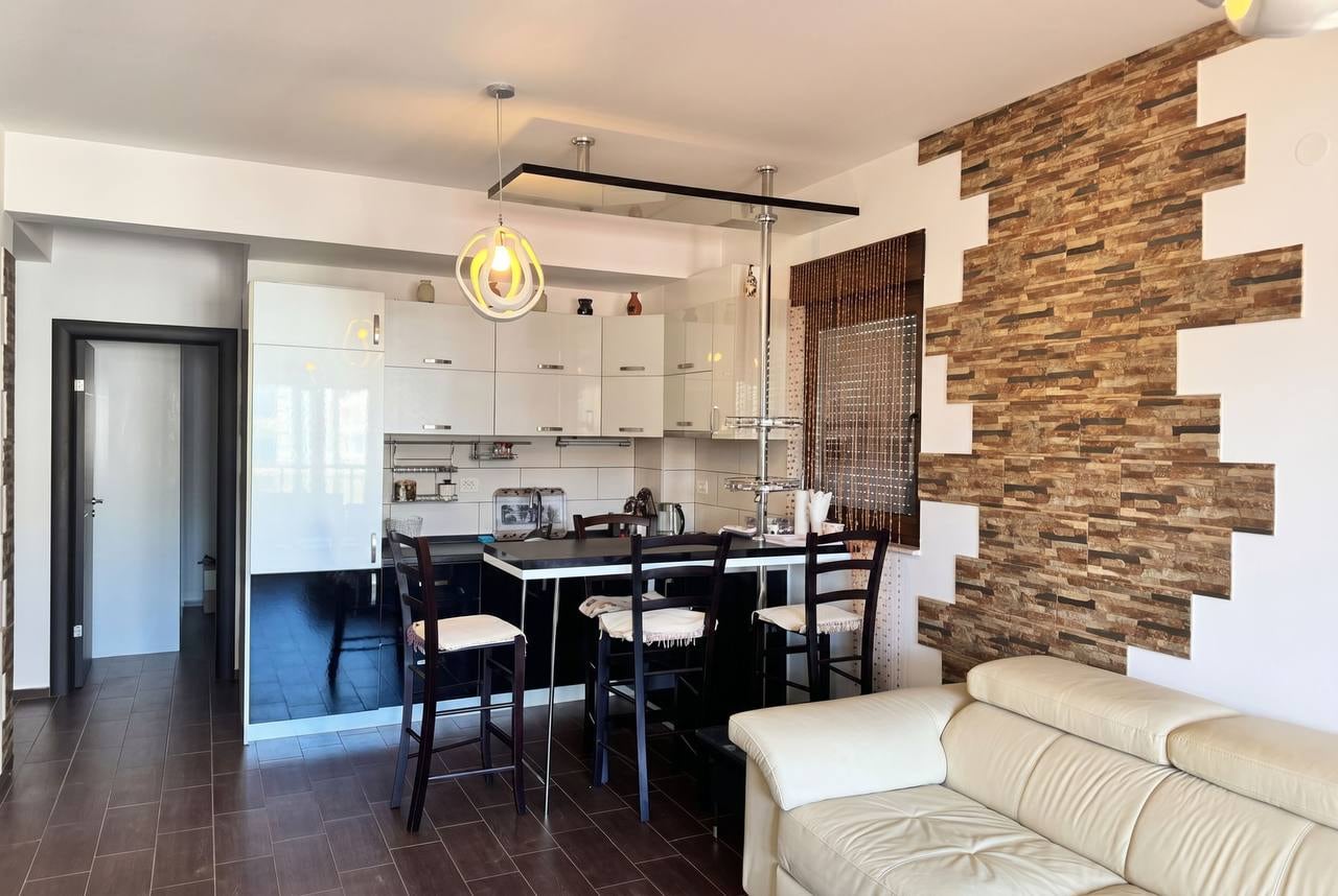 Modern kitchen-living room with a bar counter and stone finish in an apartment in Budva, Montenegro.