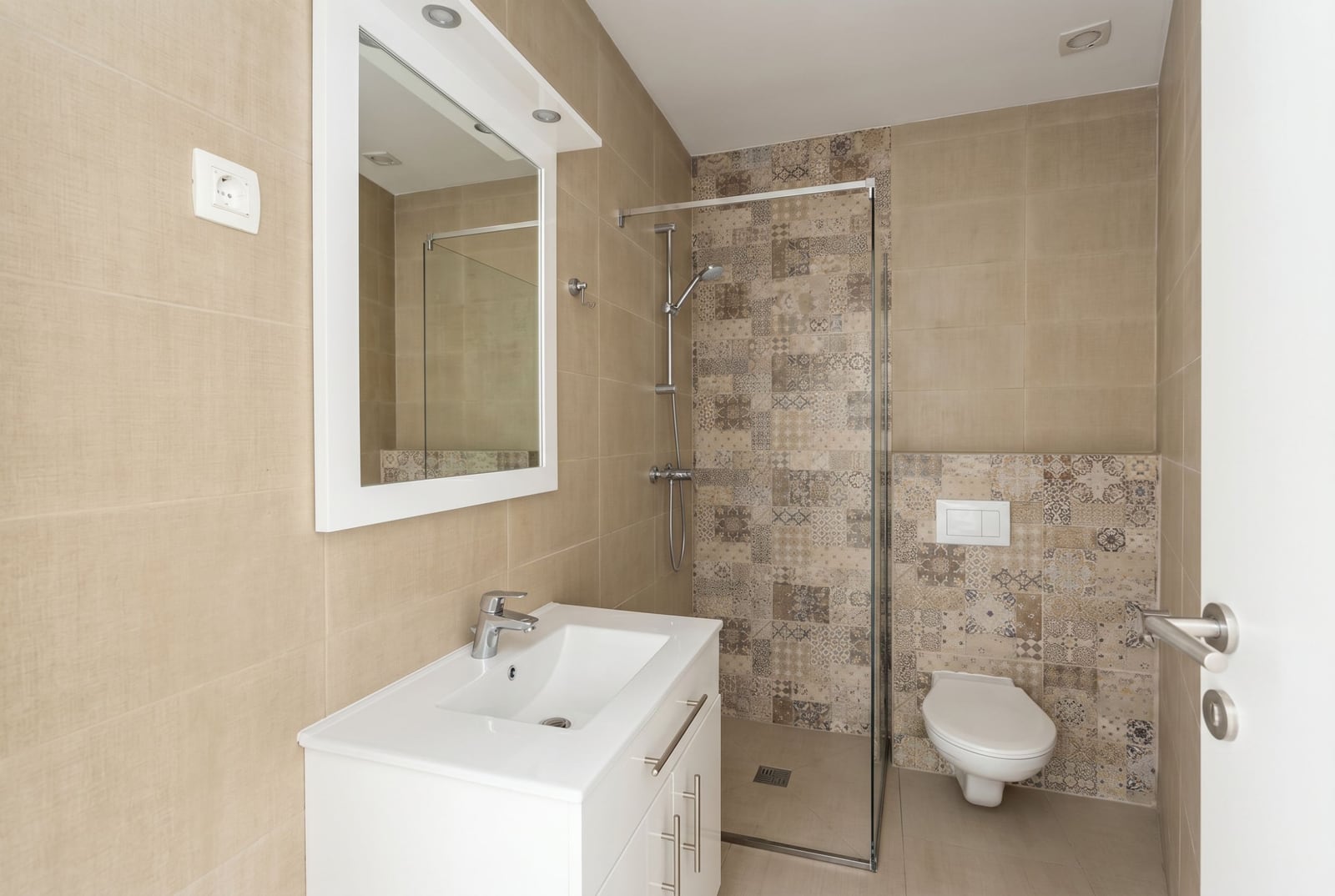 Modern bathroom in an apartment in Budva, Montenegro: shower cabin, vanity with sink, and patterned tile.