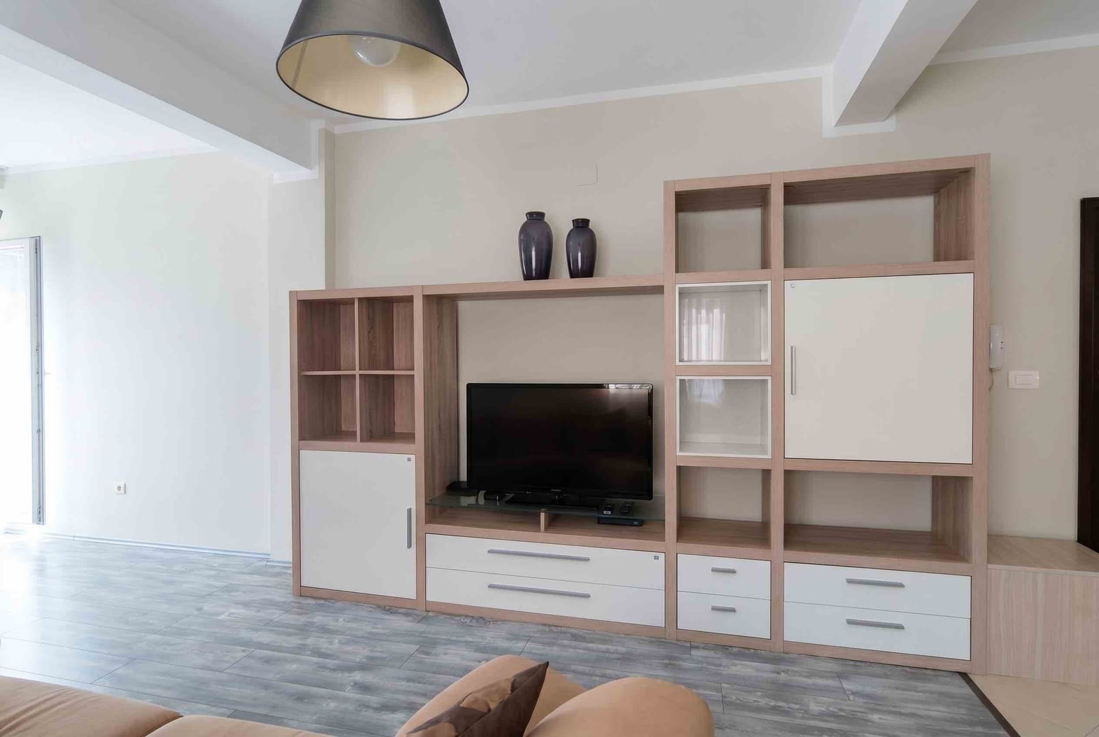 Modern living room with furniture set and TV in an apartment, Becici, Montenegro. Bright interior with laminate flooring.