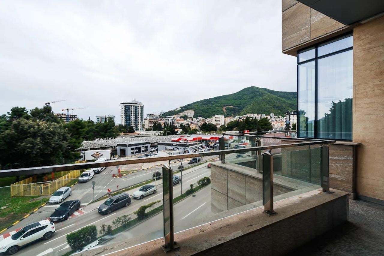 View from the balcony of a modern apartment in Budva, Montenegro: city panorama, mountains, and urban infrastructure.