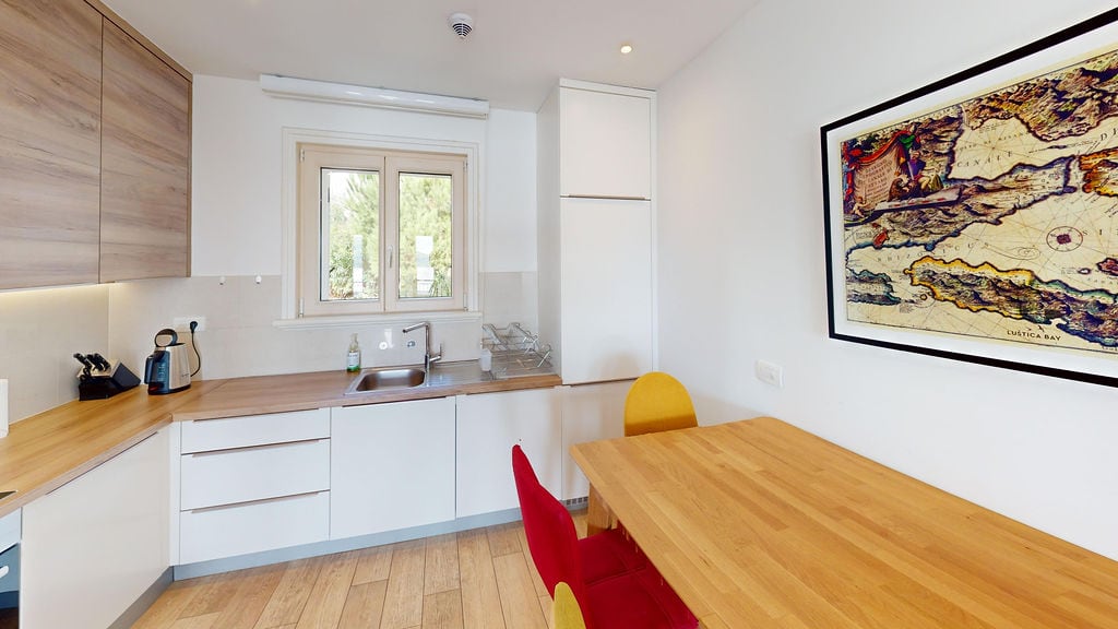Modern kitchen with wooden finishes and dining area in an apartment, Luštica, Montenegro.