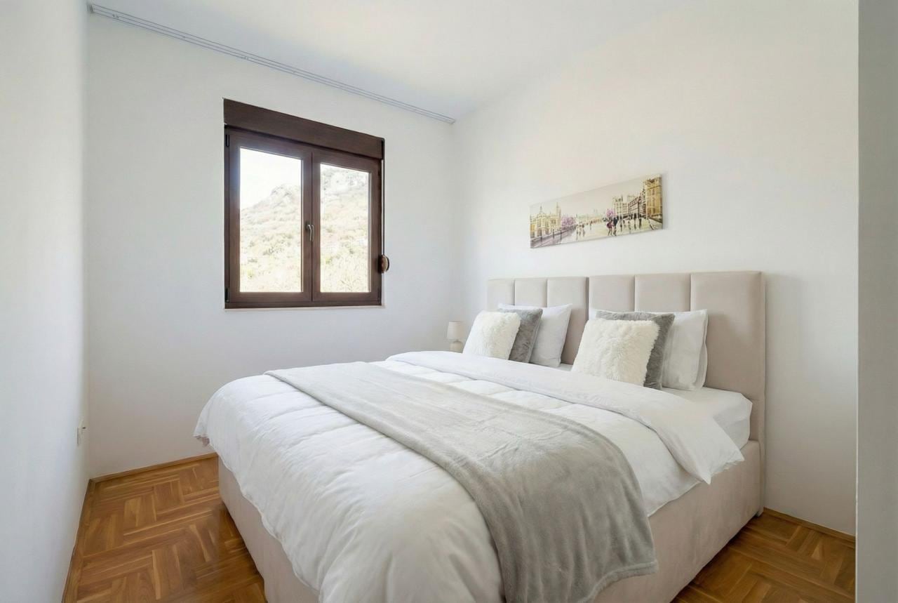 Bright bedroom with a double bed, parquet flooring, and a mountain view in an apartment in Budva, Montenegro.