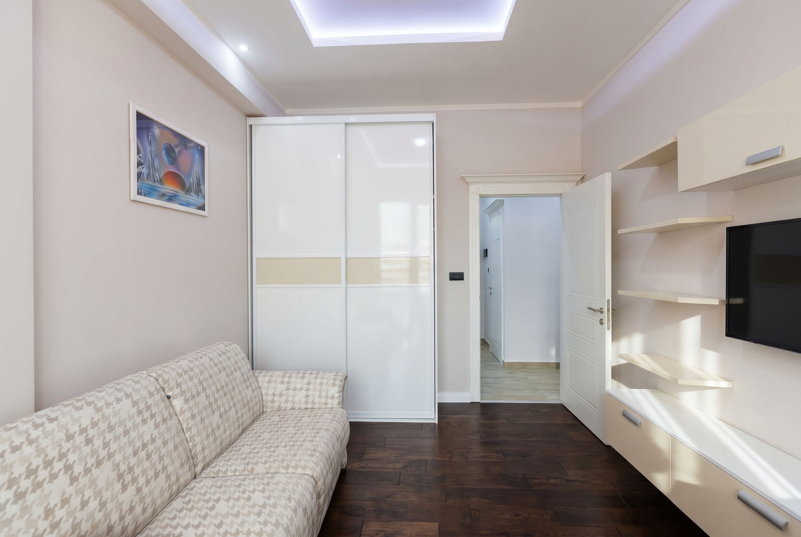 Living room in an apartment in Budva, Montenegro: light-colored sofa, built-in wardrobe, TV area, and modern finishes.