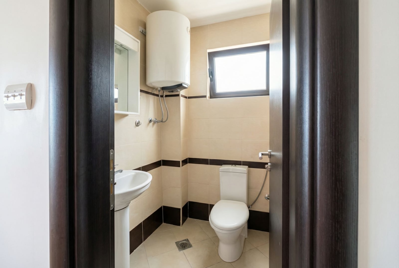 Bathroom in an apartment in Bečići, Montenegro: light tiles, plumbing fixtures, water heater, and a window in the bathroom.