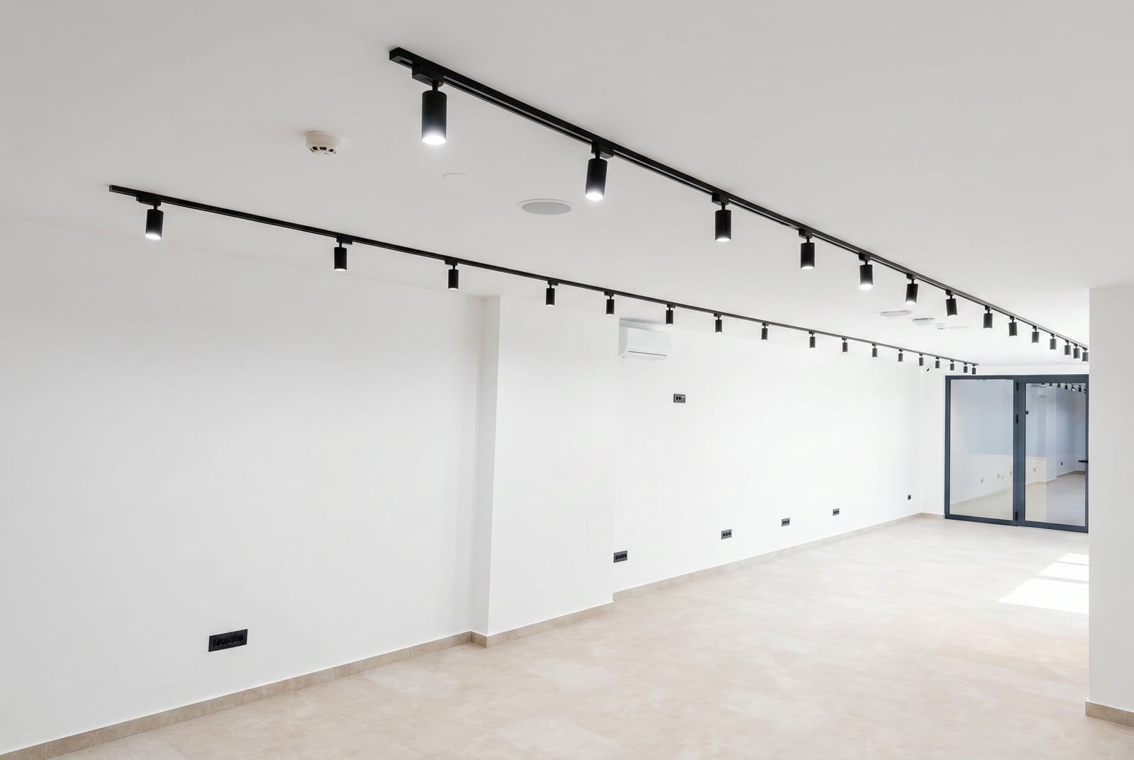 Bright office space in Budva, Montenegro: modern renovation, track lighting, and panoramic glass door.