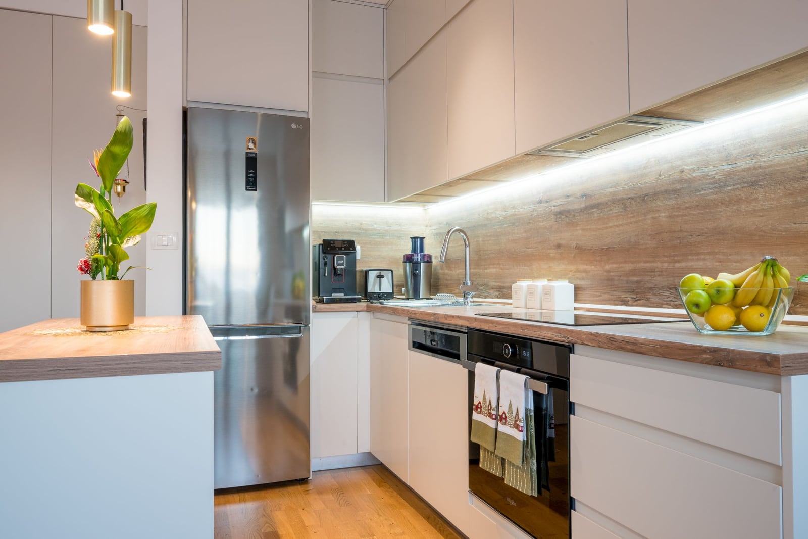 Modern kitchen in an apartment in Tivat, Montenegro: light-colored cabinets, built-in appliances, and a wooden countertop.