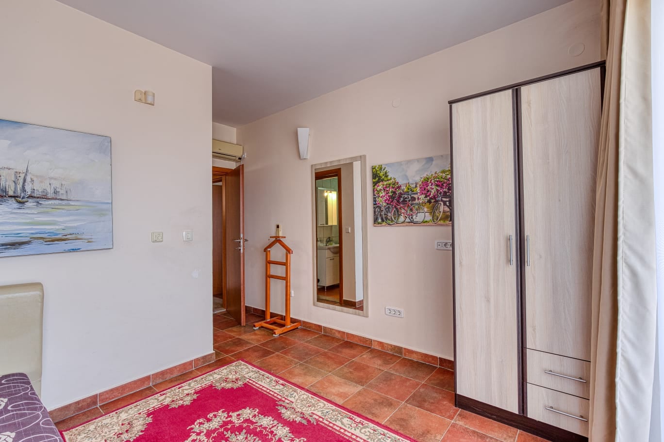 Bedroom in a villa in Bečići, Montenegro: bright room with tiled flooring, wardrobe, mirror, and wall decor.
