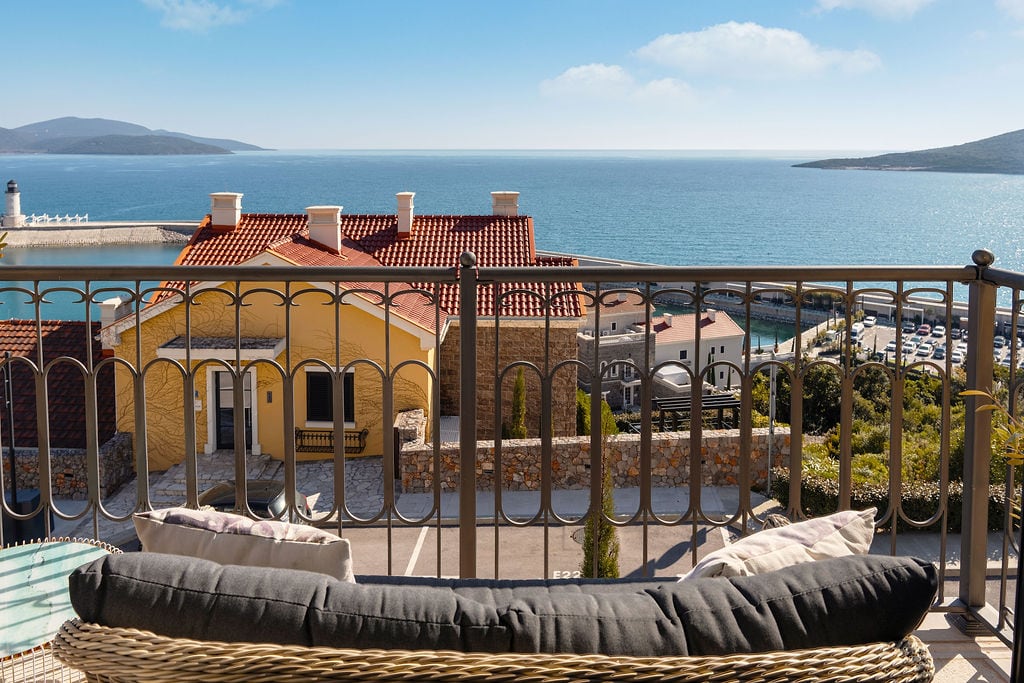 View from the balcony of a townhouse in Lustica Bay, Montenegro: panorama of the sea, yacht marina, and Mediterranean architecture.