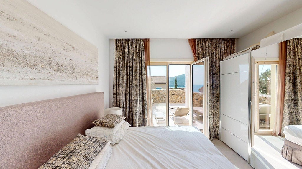 Bedroom in an apartment in Luštica, Montenegro: double bed, white wardrobe, and access to a terrace with a sea view.