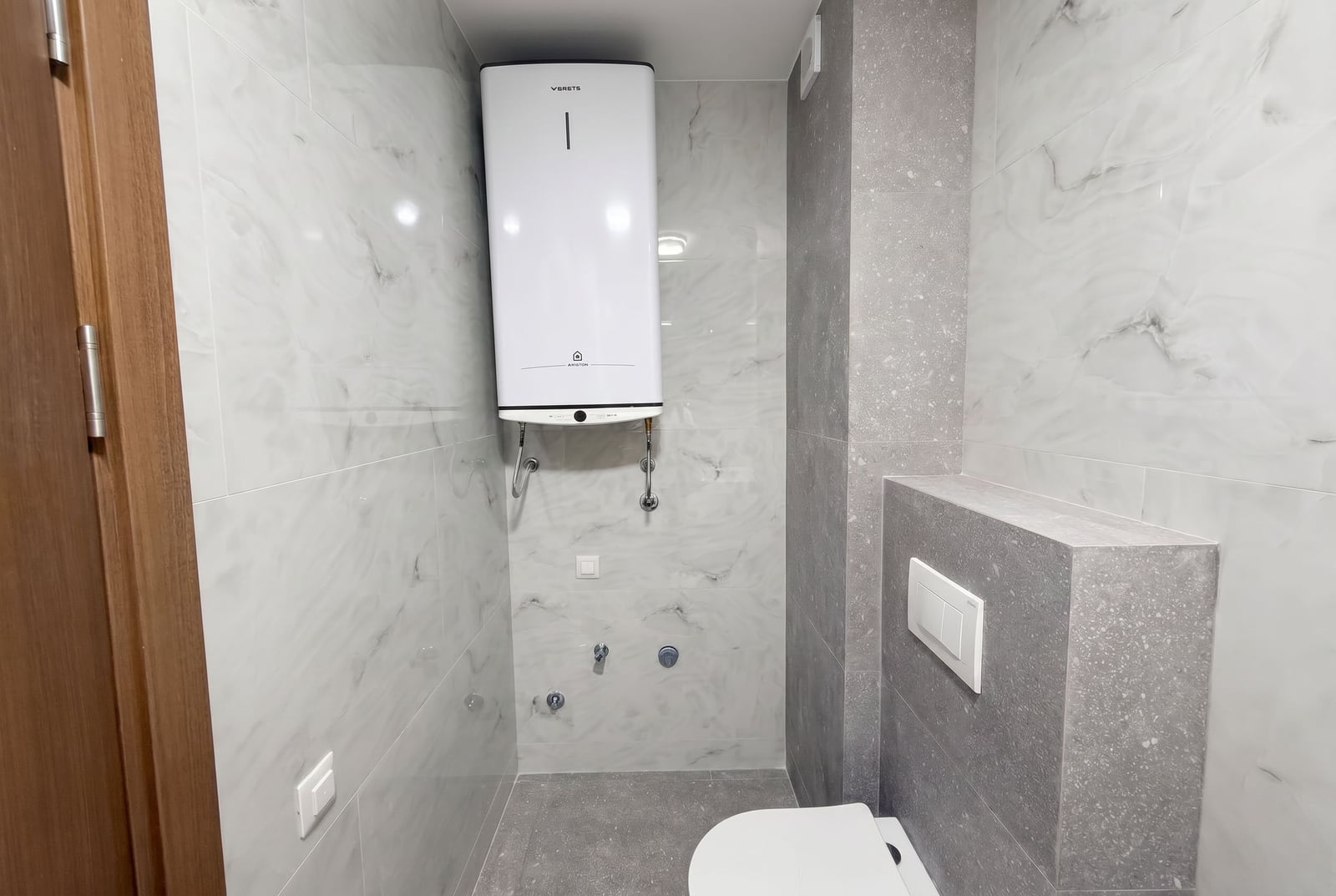 Modern bathroom with a water heater and tile finish in an apartment in Budva, Montenegro.