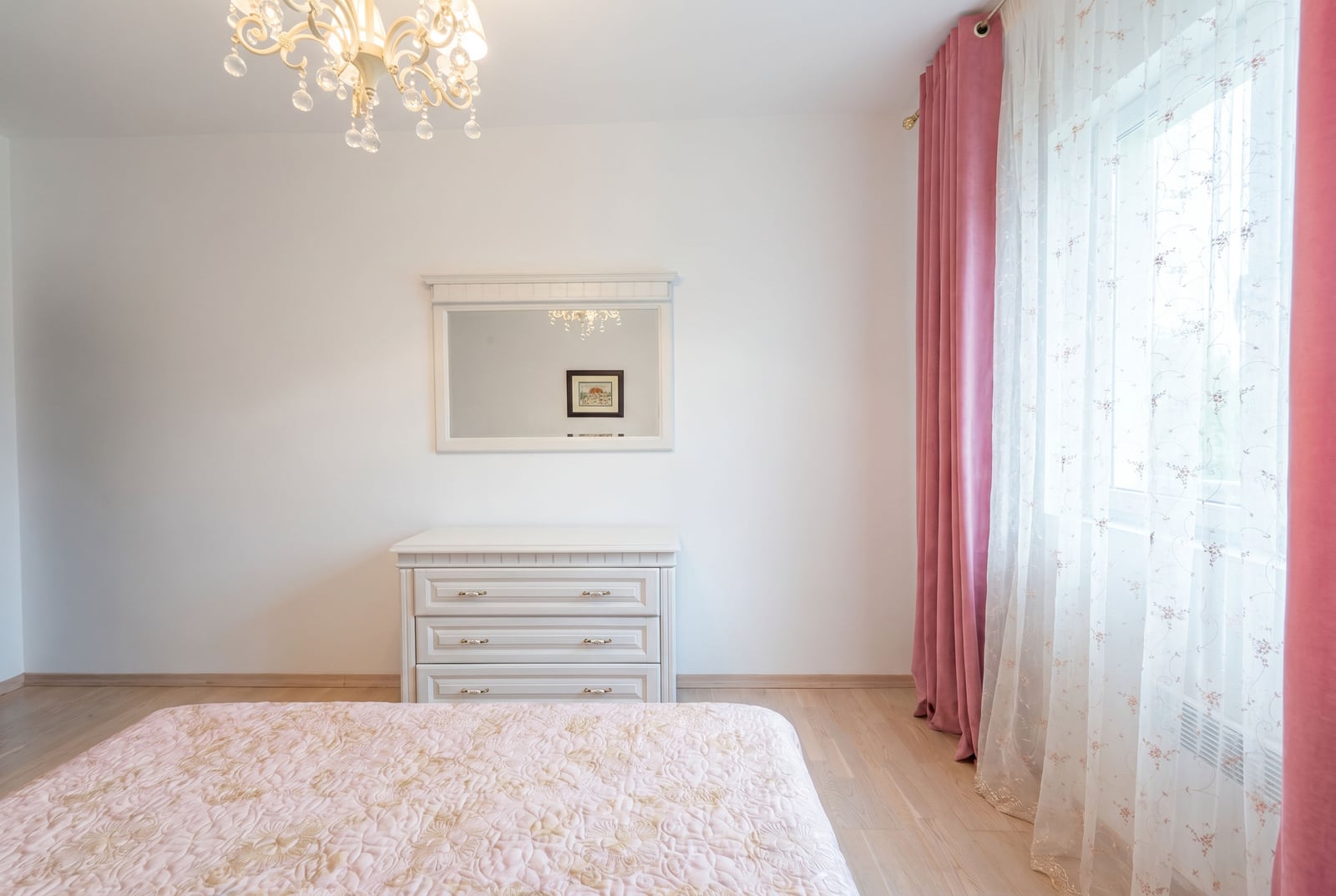 Bright bedroom in an apartment, Kumbor, Montenegro: white furniture, dresser with a mirror, bed, and pink curtains.