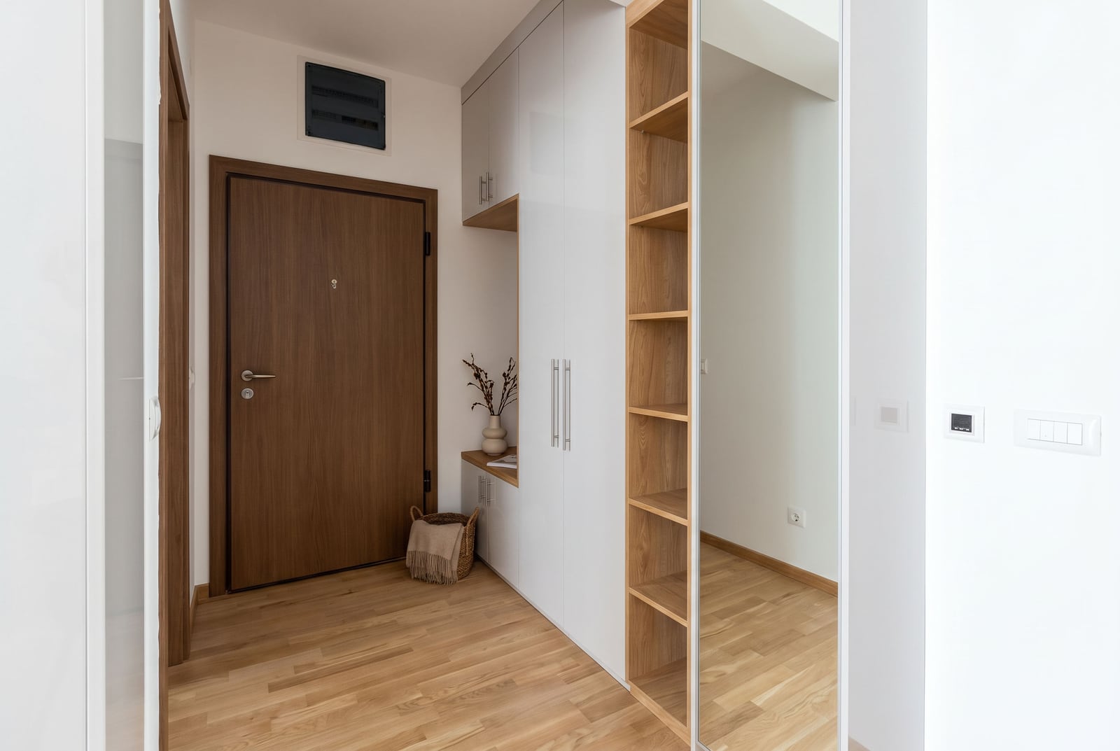 Modern hallway with a built-in wardrobe and mirror in an apartment in Budva, Montenegro. Bright interior with wood finishes.