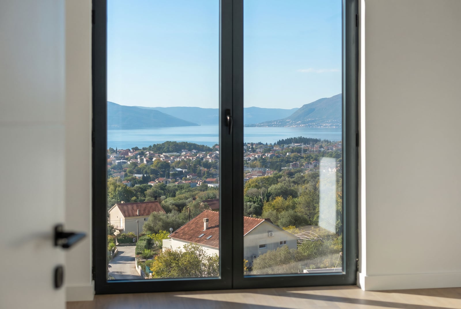 Panoramic view of the Bay of Kotor and mountains from the window of a modern living room in a townhouse, Kavač, Montenegro.