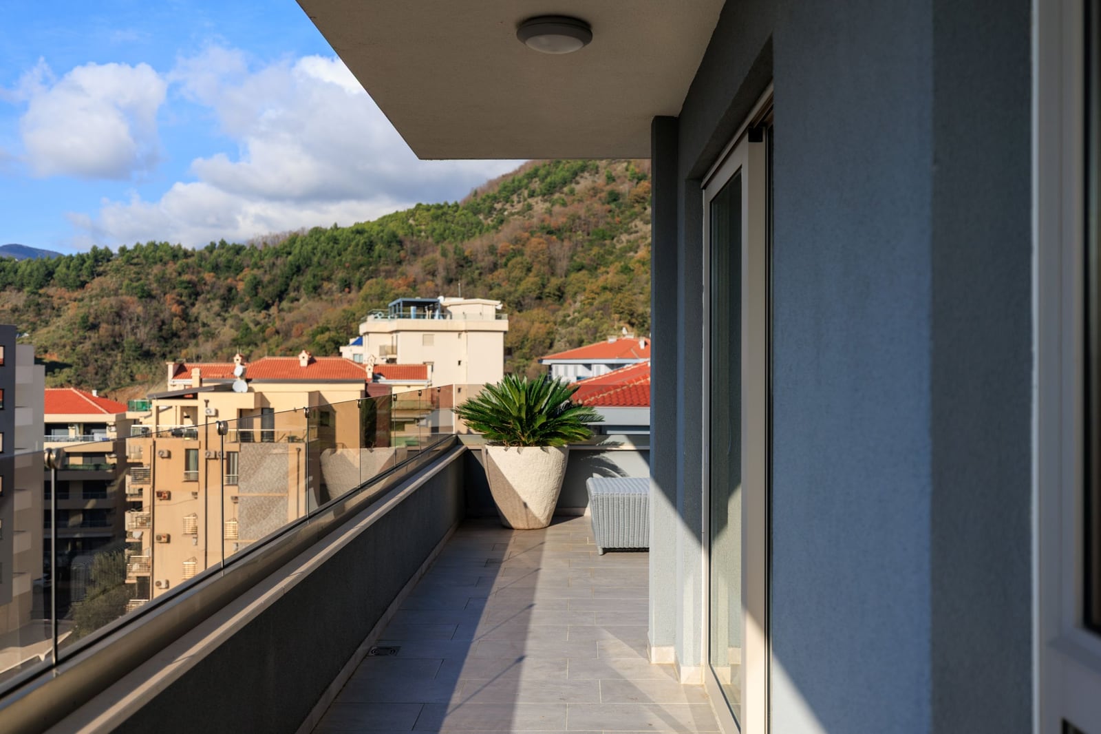 Spacious penthouse balcony in Bečići, Montenegro, with panoramic mountain views and modern furniture.