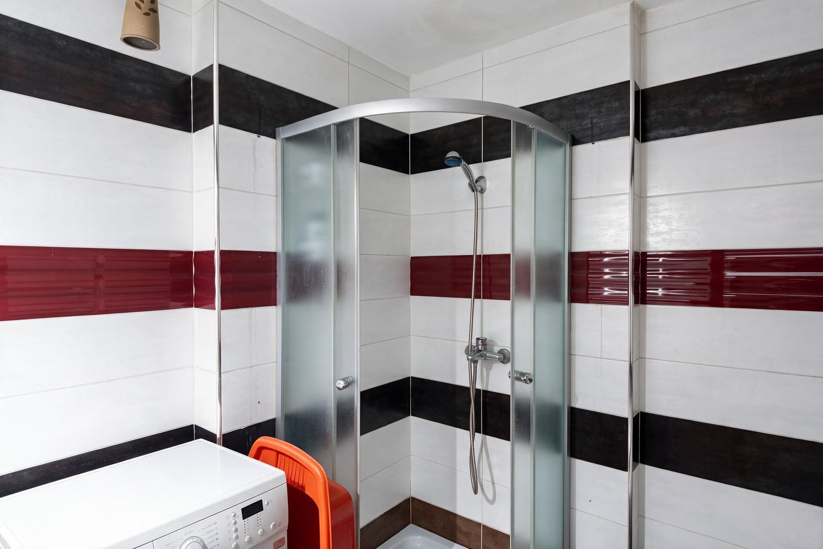 Modern corner shower cabin and washing machine in the bathroom of an apartment in Budva, Montenegro.