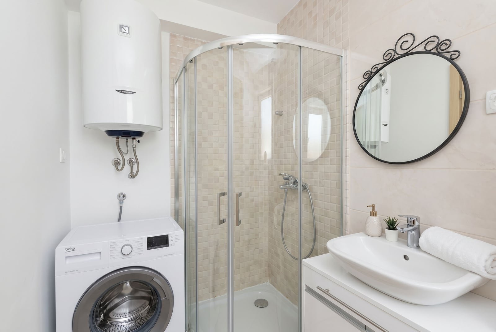 Bathroom in an apartment in Bečići, Montenegro: shower cabin, Beko washing machine, water heater, and countertop sink.