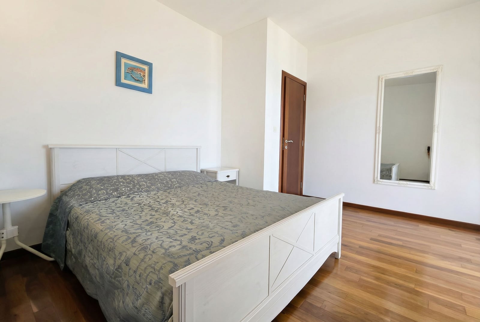 Bright bedroom with a double bed and mirror in an apartment in Tivat, Montenegro. Parquet flooring, modern style.
