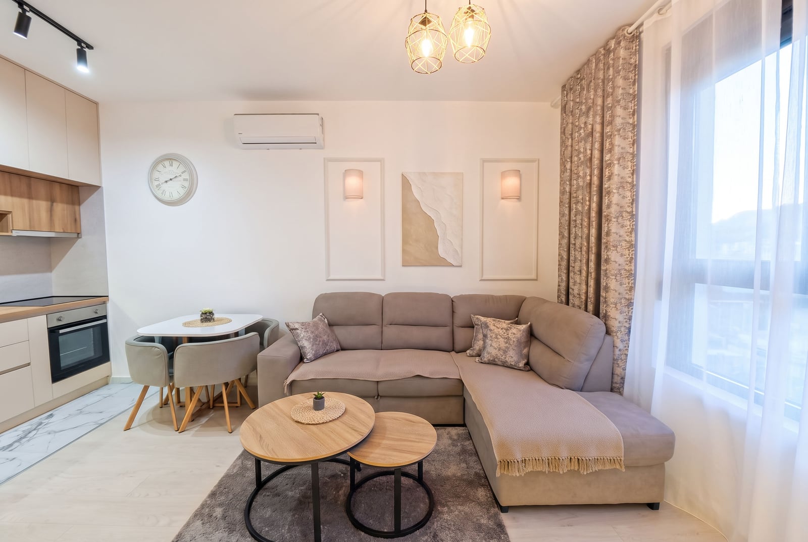 Living room with a beige sectional sofa, wooden coffee tables, and an open kitchen area on the left.