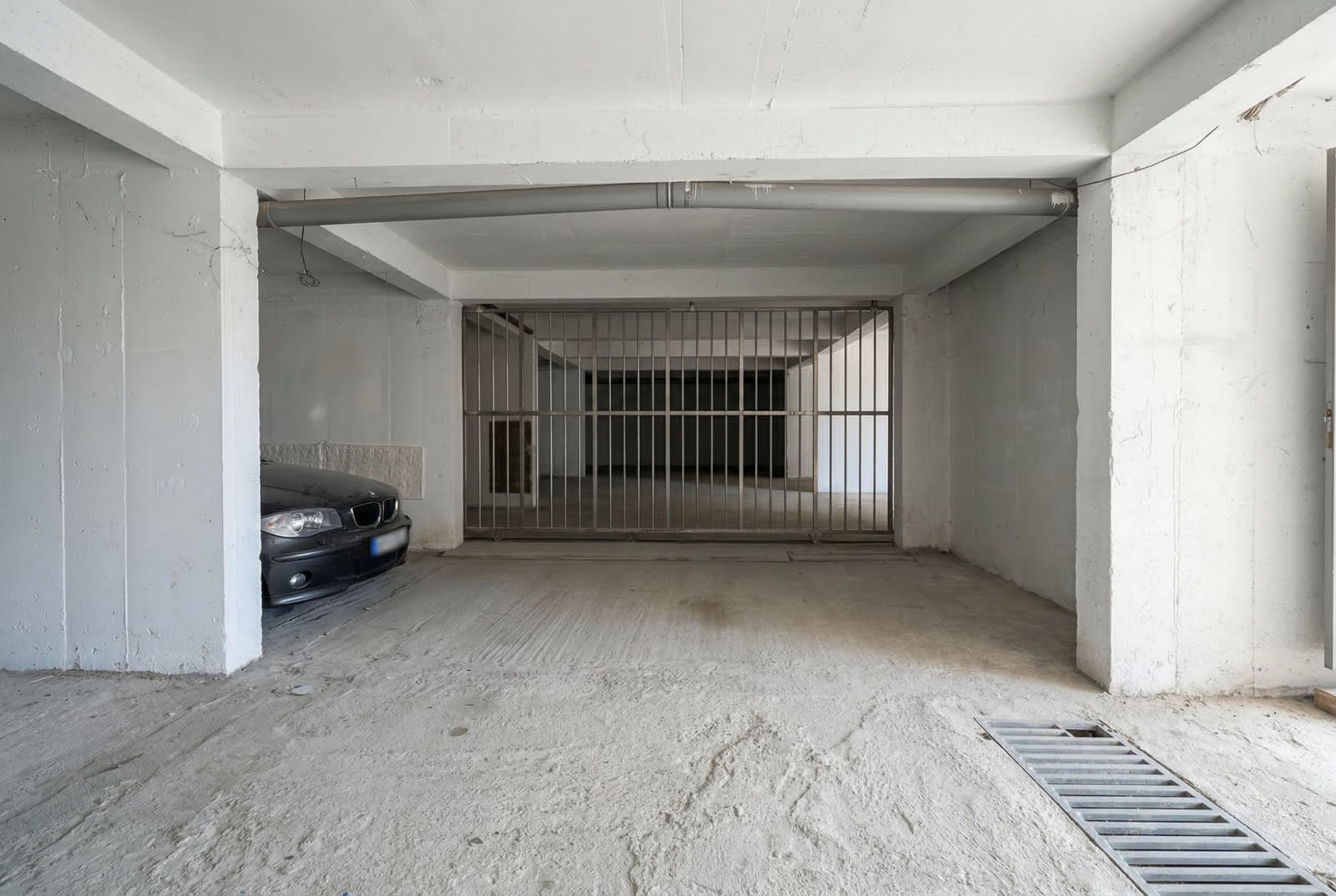 Covered parking space in a residential complex in Budva, Montenegro: concrete garage with a metal grille.