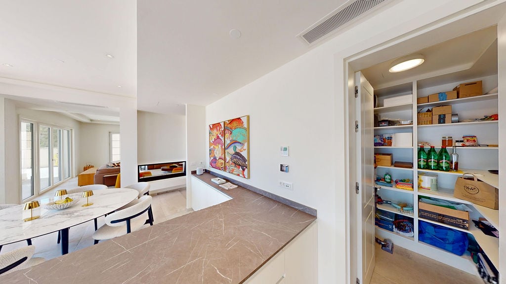 Modern kitchen with a pantry and dining area in a villa in Luštica, Montenegro: marble countertop and light interior.