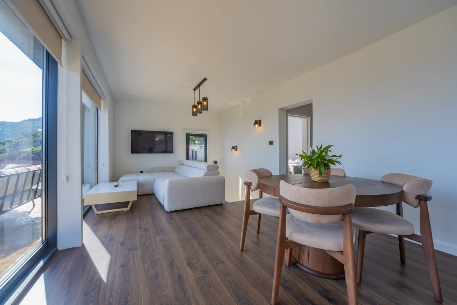 Modern living room with panoramic windows and a dining area in a villa in Budva, Montenegro. Bright interior with furniture.