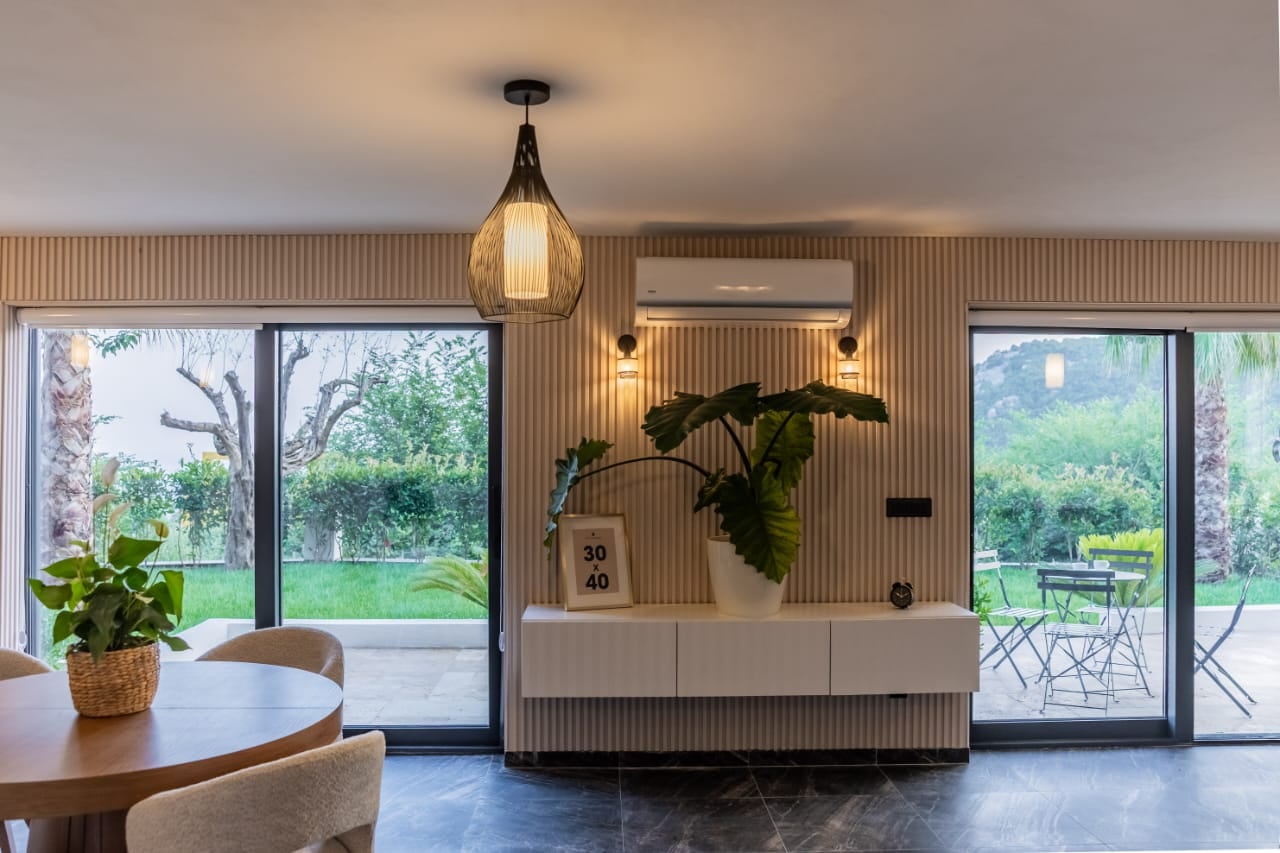 Modern villa living room in Budva, Montenegro: panoramic windows, slatted wall, white console, and garden view.