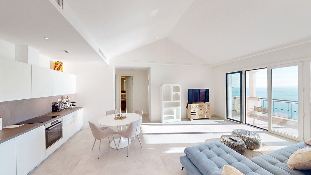Bright living room with kitchen in Lustica Bay apartments, Montenegro: panoramic sea view, modern furniture, and terrace.