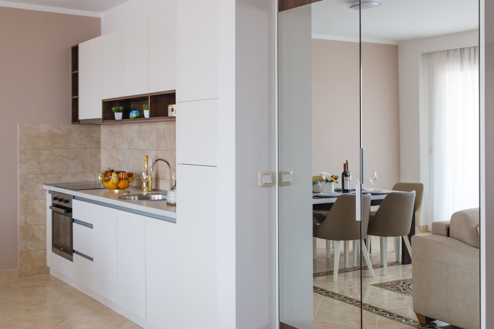 Modern white kitchen and dining area in an apartment in Becici, Montenegro: stylish interior with high-quality finishes.