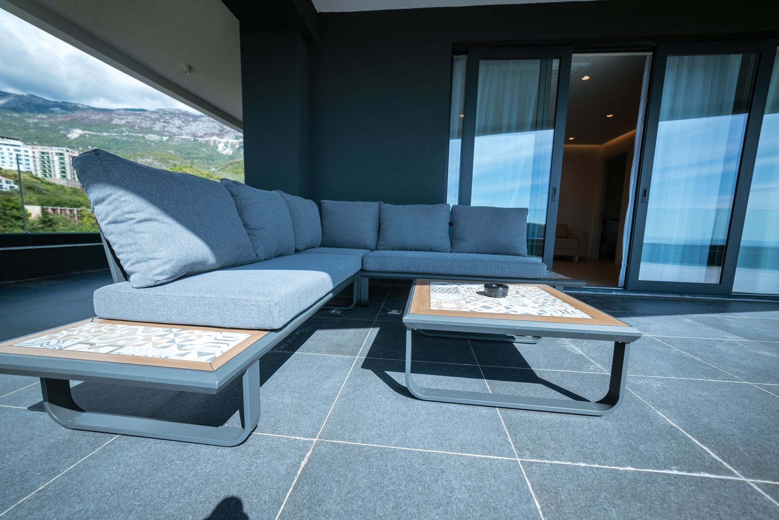 Apartment terrace in Bečići, Montenegro: modern garden furniture, panoramic mountain views, and stylish tile finishing.