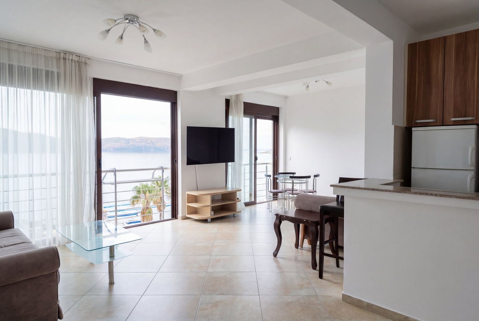 Living room with kitchen in an apartment in Rafailovici, Montenegro: panoramic sea view, modern furniture, and a bright interior.