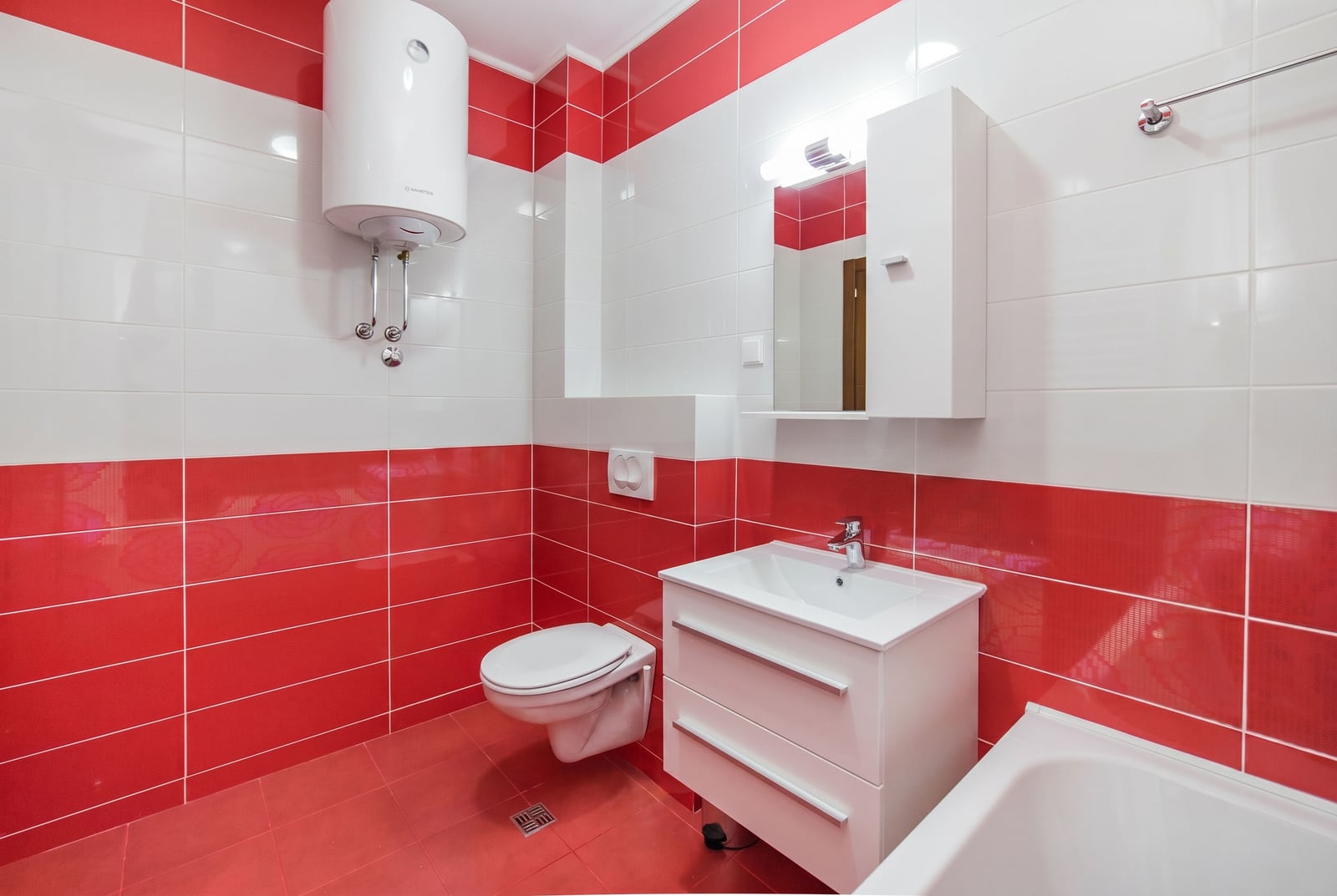 Modern bathroom with red and white tiles in an apartment, Bečići, Montenegro: sanitary ware, water heater, and vanity unit.