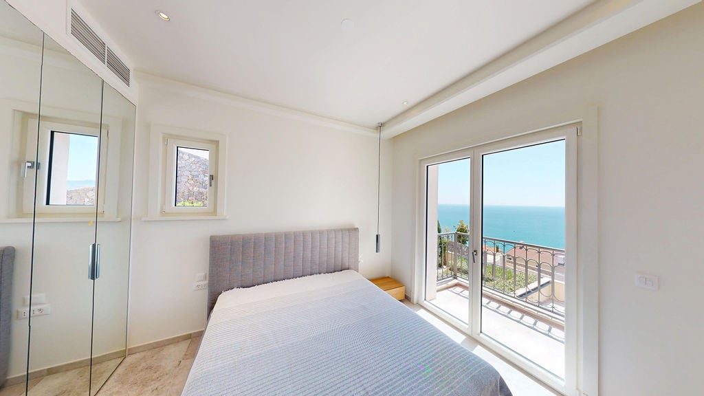 Modern bedroom with a double bed and panoramic sea view in a residential complex, Luštica, Montenegro.