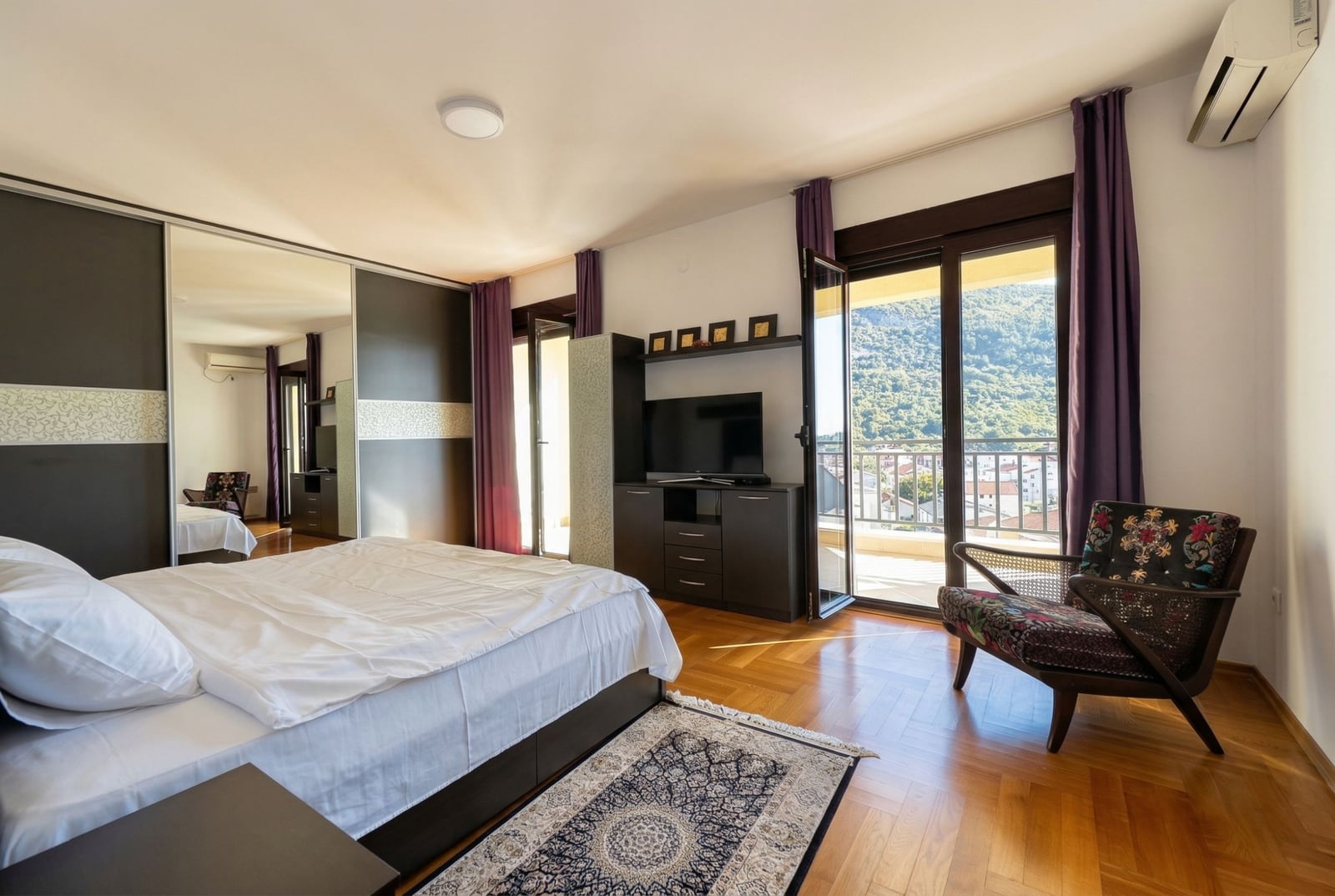 Bedroom in an apartment in Budva, Montenegro: double bed, mirrored wardrobe, mountain view, and terrace.