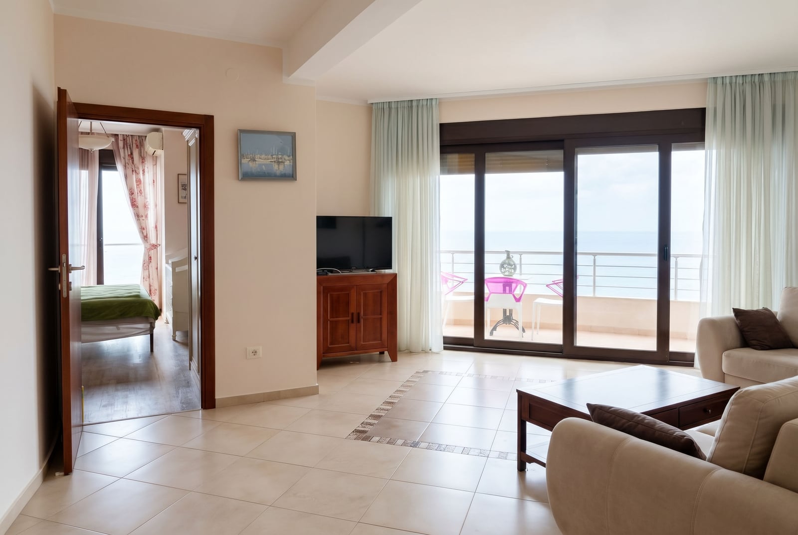 Living room in an apartment in Bar, Montenegro: bright room with balcony access, sea view, and wooden furniture.