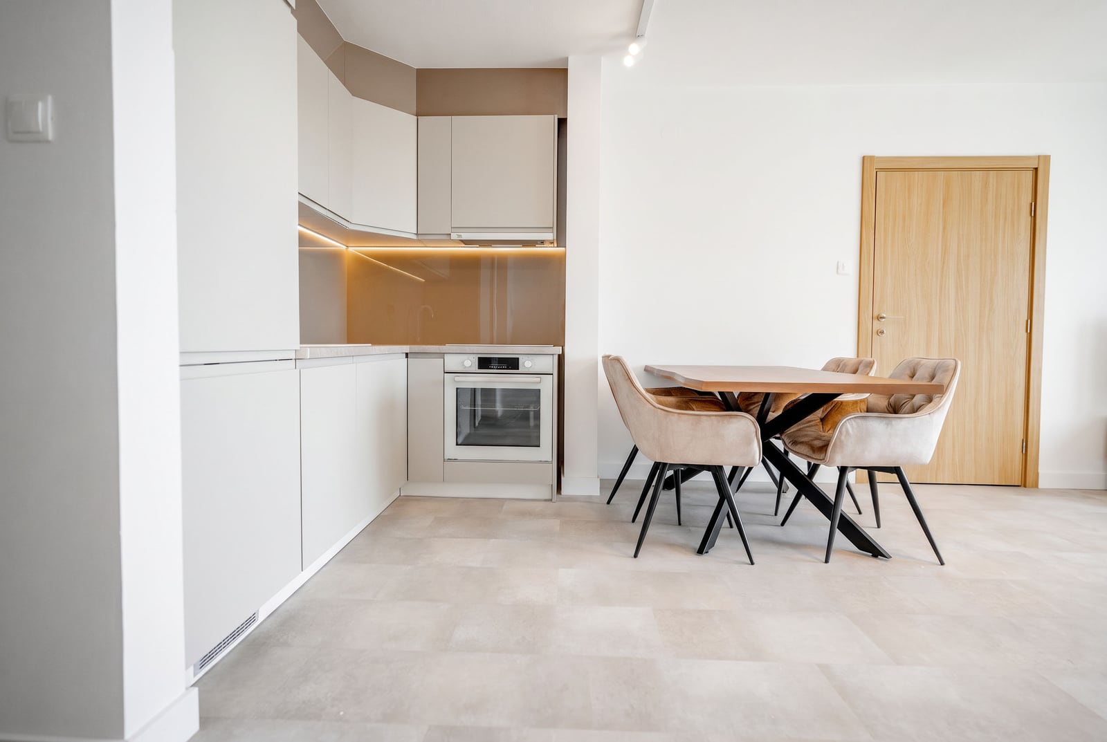 Modern kitchen-dining area in an apartment, Sveti Stefan, Montenegro: light-colored cabinetry, dining table, and upholstered chairs.