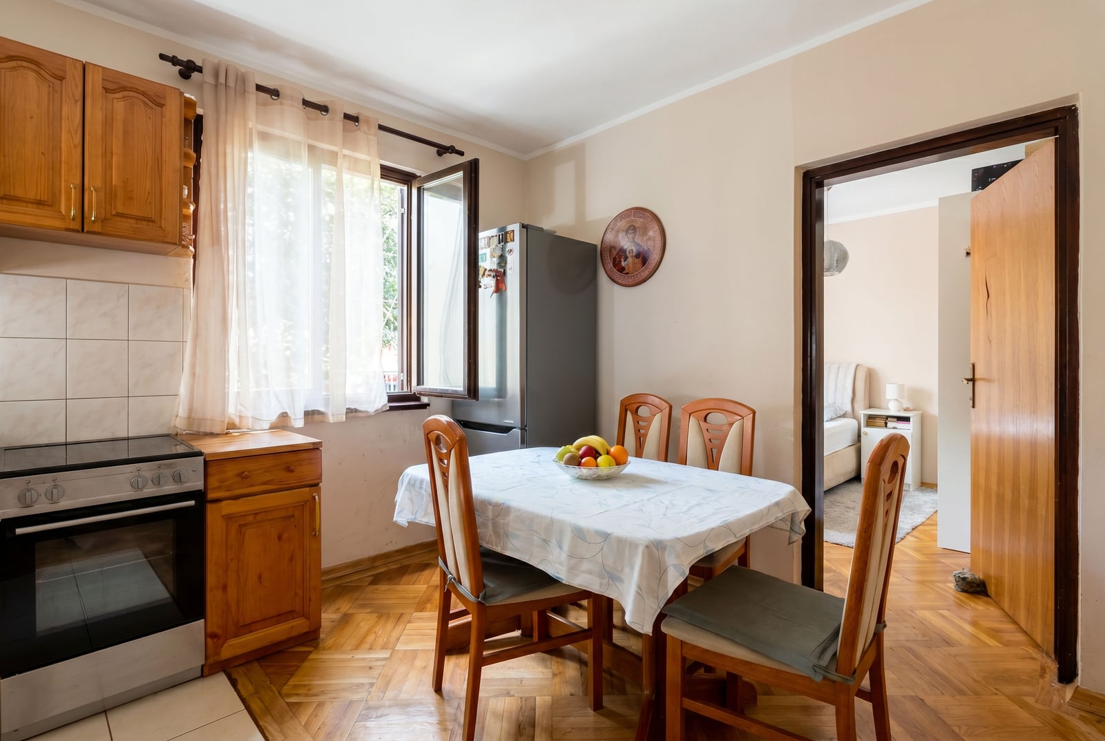 Cozy kitchen with wooden furniture and a dining area in an apartment for sale in Budva, Montenegro.