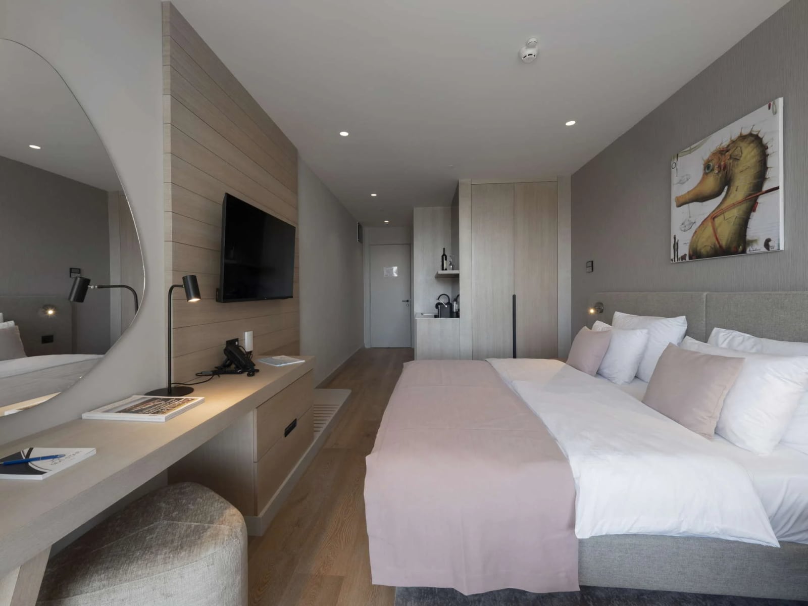 Modern bedroom featuring a large bed, wood-paneled TV wall, and a long desk area.
