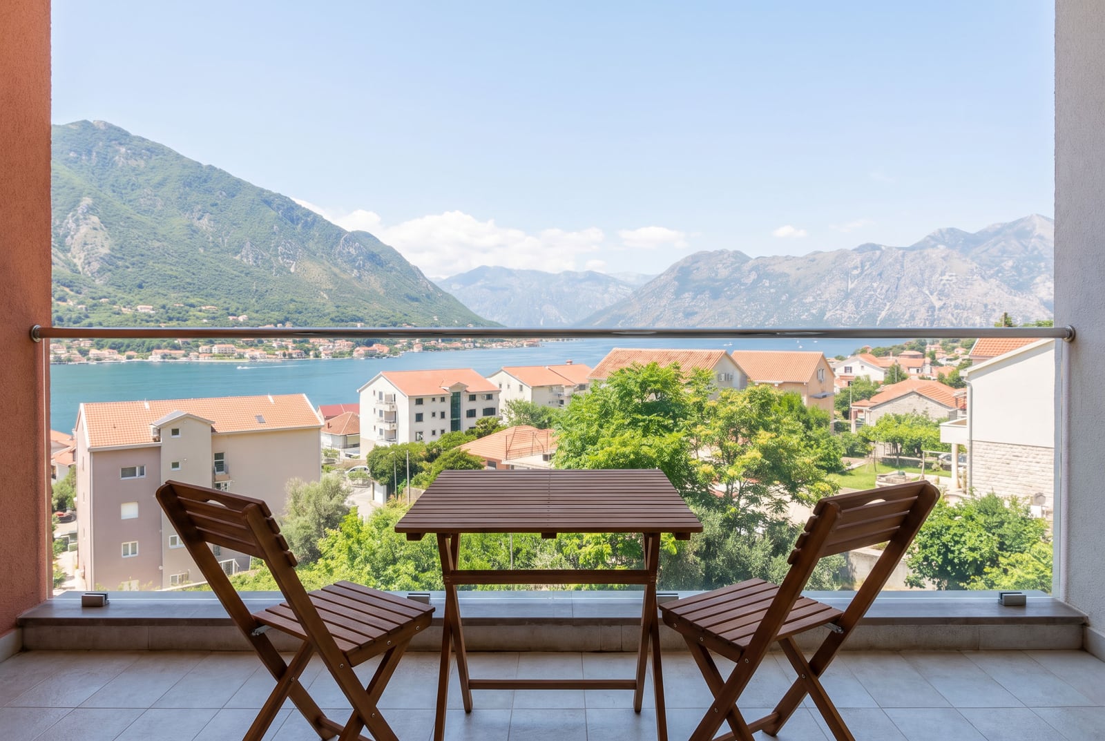 Balcony with wooden furniture and panoramic views of the Bay of Kotor and mountains in Dobrota, Montenegro.