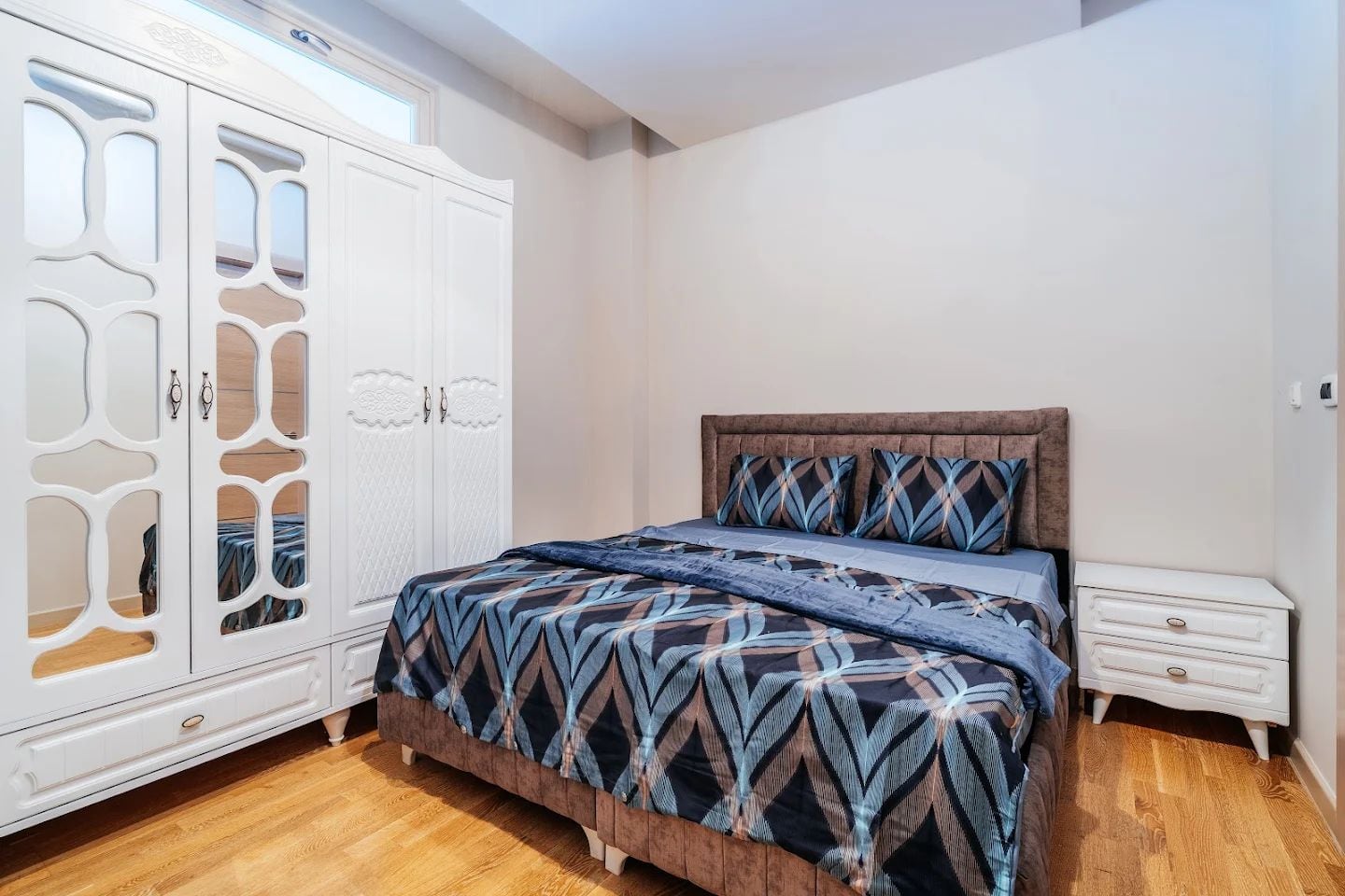 Bright bedroom with a double bed and a white wardrobe in an apartment for sale in Budva, Montenegro.