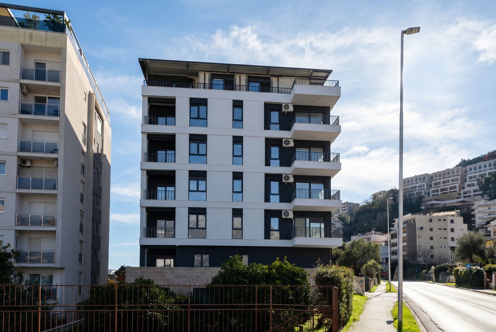 Modern apartment building with balconies in Budva, Montenegro, street view of the building facade.